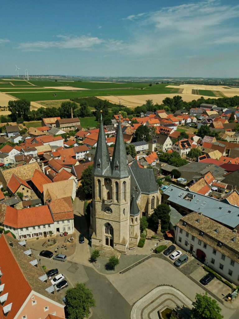 pexels photo 17601471 17601471 A stunning aerial view of a Gothic church in Flonheim, Germany, set in a quaint town square.