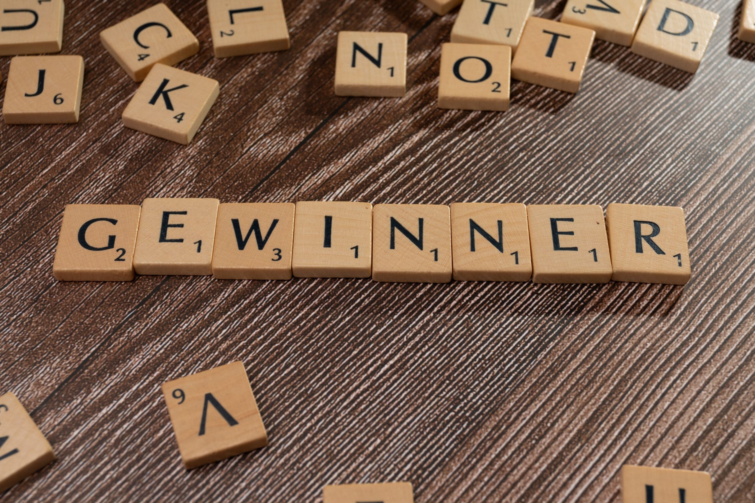 Treppenlift Erfahrungen – Ehrliche Erfahrungen, Kosten, Vorteile und wichtige Tipps vor dem Kauf Scrabble tiles forming the word 'Gewinner' meaning winner on a wooden table.