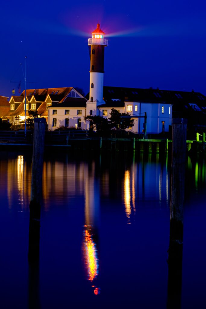 Long exposure of a lighthouse and buildings reflecting on calm waters at sunset on Insel Poel.