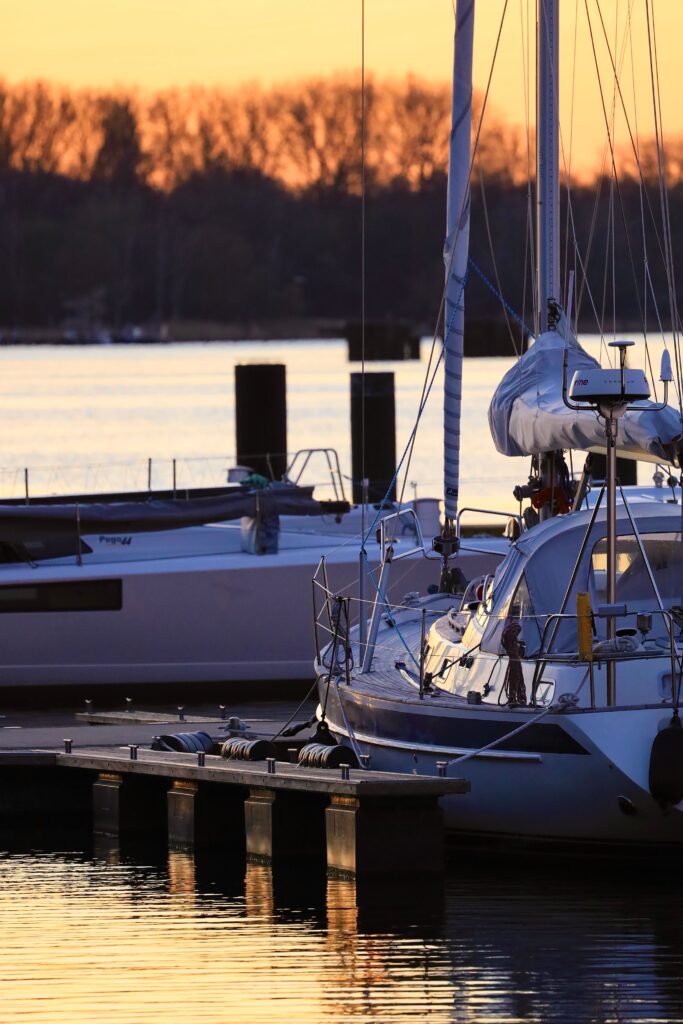 Peaceful harbor scene with sailboats at sunset, showcasing tranquil water and vibrant sky.