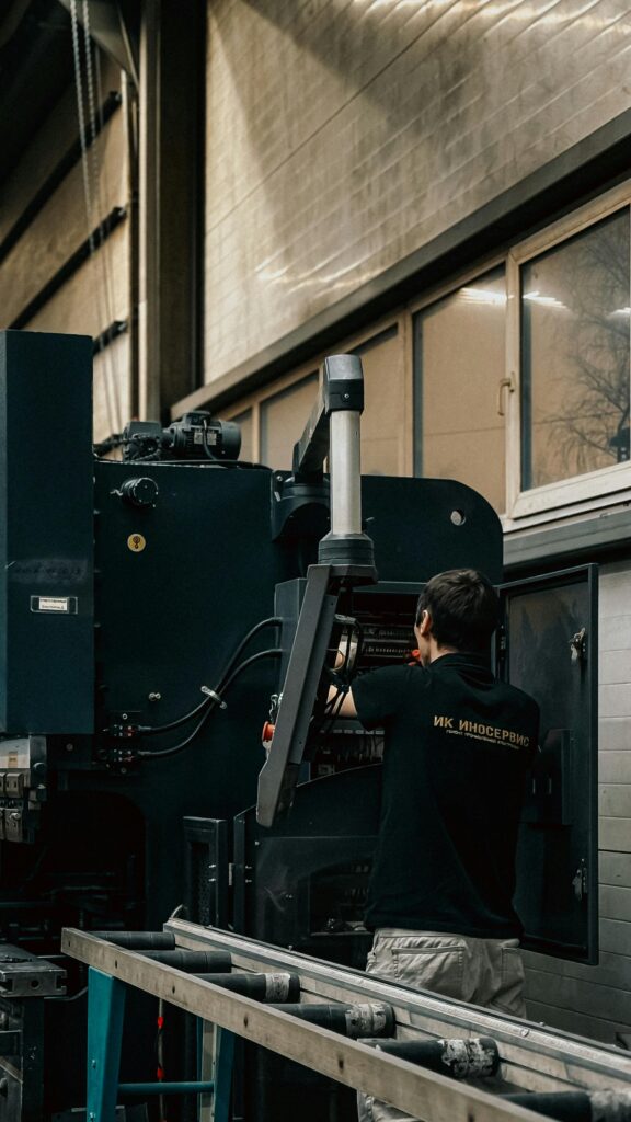 pexels photo 35072825 35072825 A worker in an industrial setting operates and adjusts a large machine.