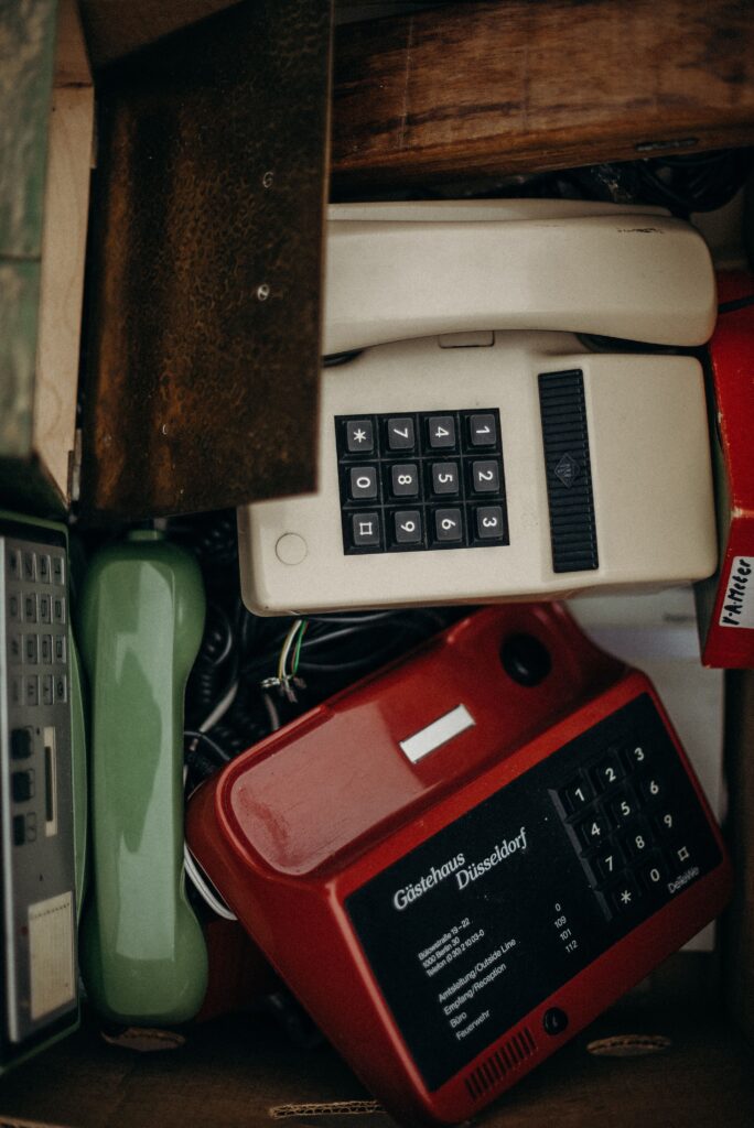 A collection of vintage telephones featuring dial pads in a box, showcasing retro technology.