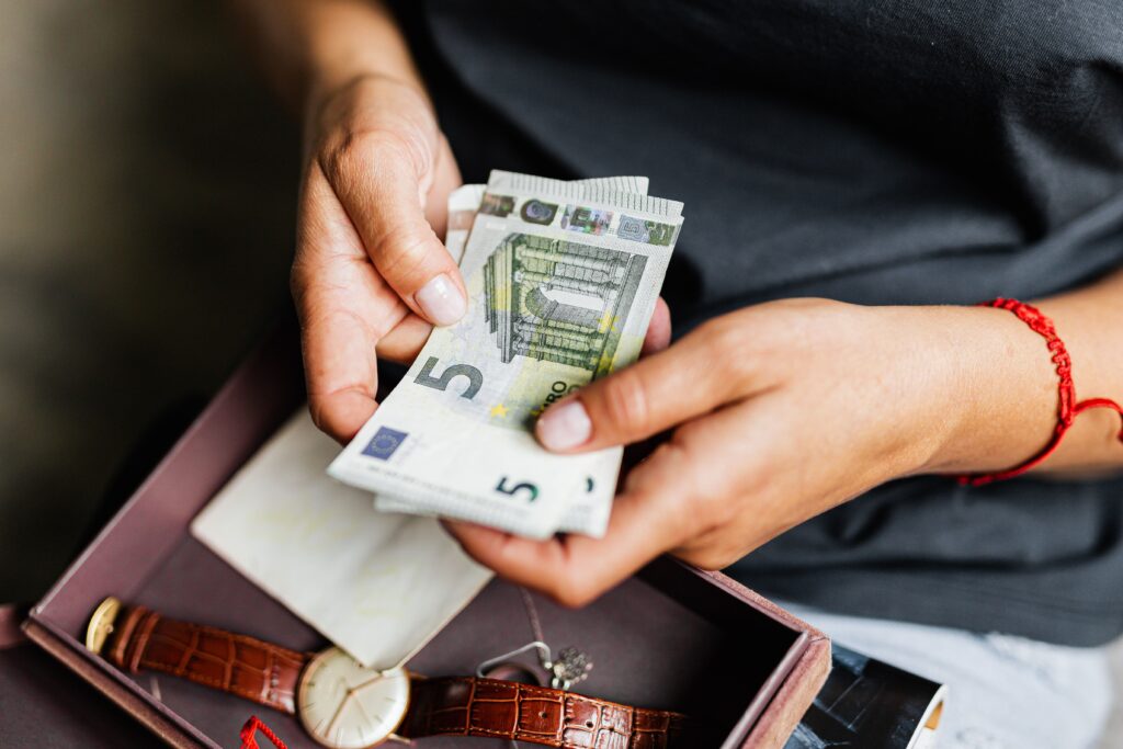 pexels photo 4960141 4960141 Close-up of hands counting euro notes above a wristwatch in a box.