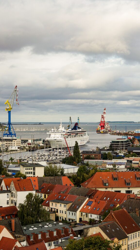 Aerial view of a bustling harbor with ferries and vibrant red-tiled rooftops under a cloudy sky.