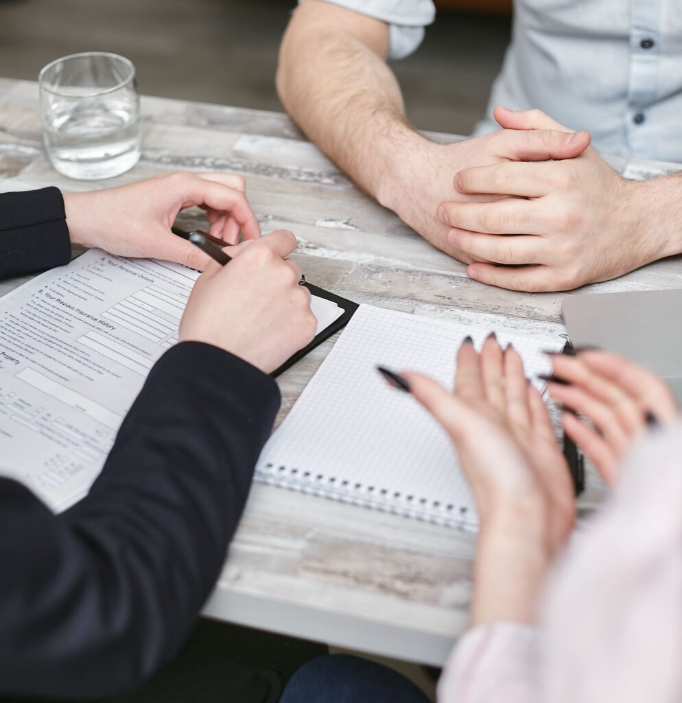 pexels photo 7734578 7734578 Close-up view of a team meeting with documents and notebooks on a wooden desk.