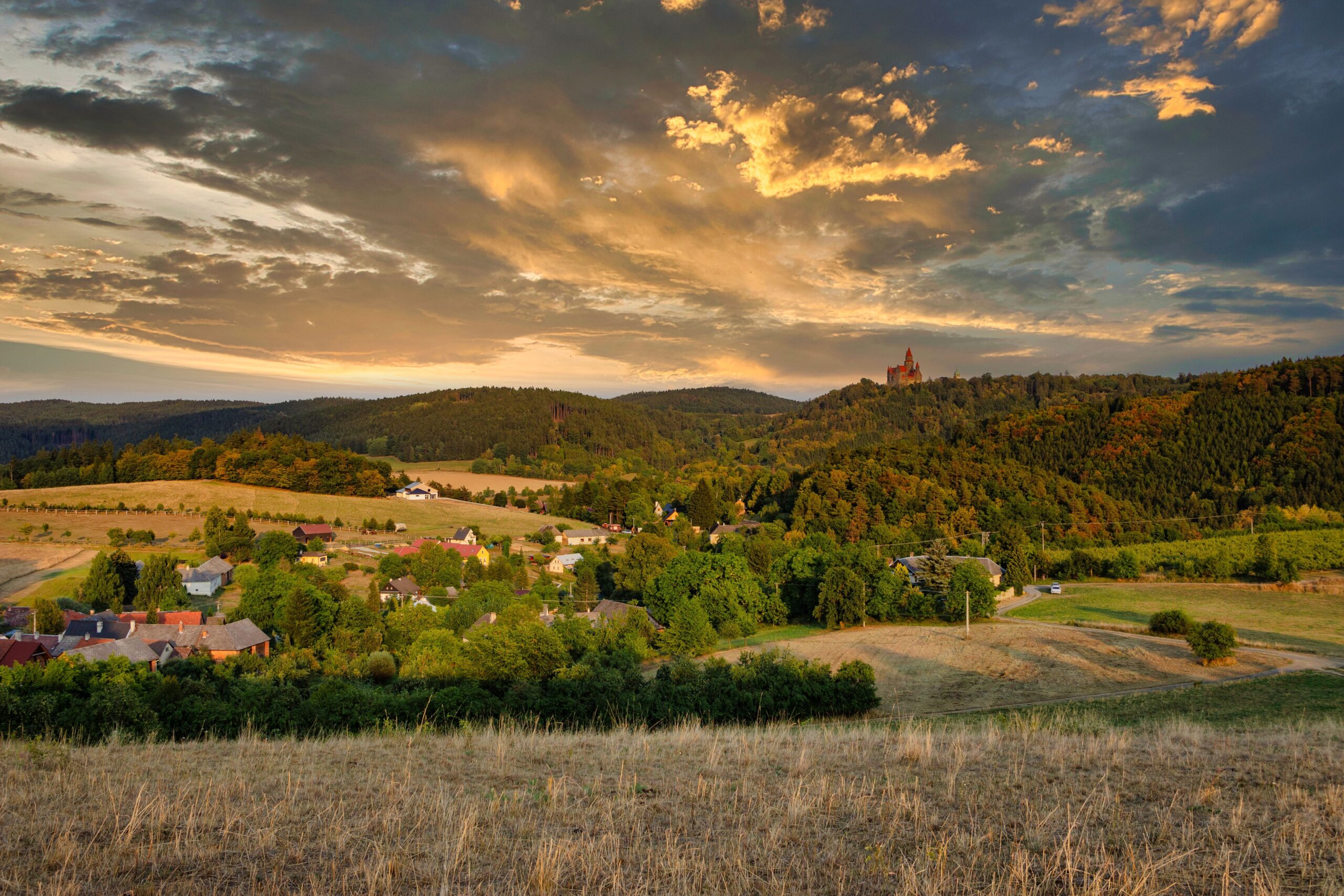 Treppenlift Kosten Thüringen – Preise, Kostenfaktoren und Sparmöglichkeiten im Überblick Scenic view of a tranquil Czech village surrounded by lush hills at sunset, under an orange sky.