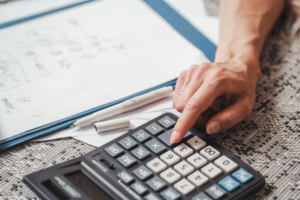 pexels photo 9052475 9052475 A hand using a calculator on top of documents, indicating financial calculation or analysis.