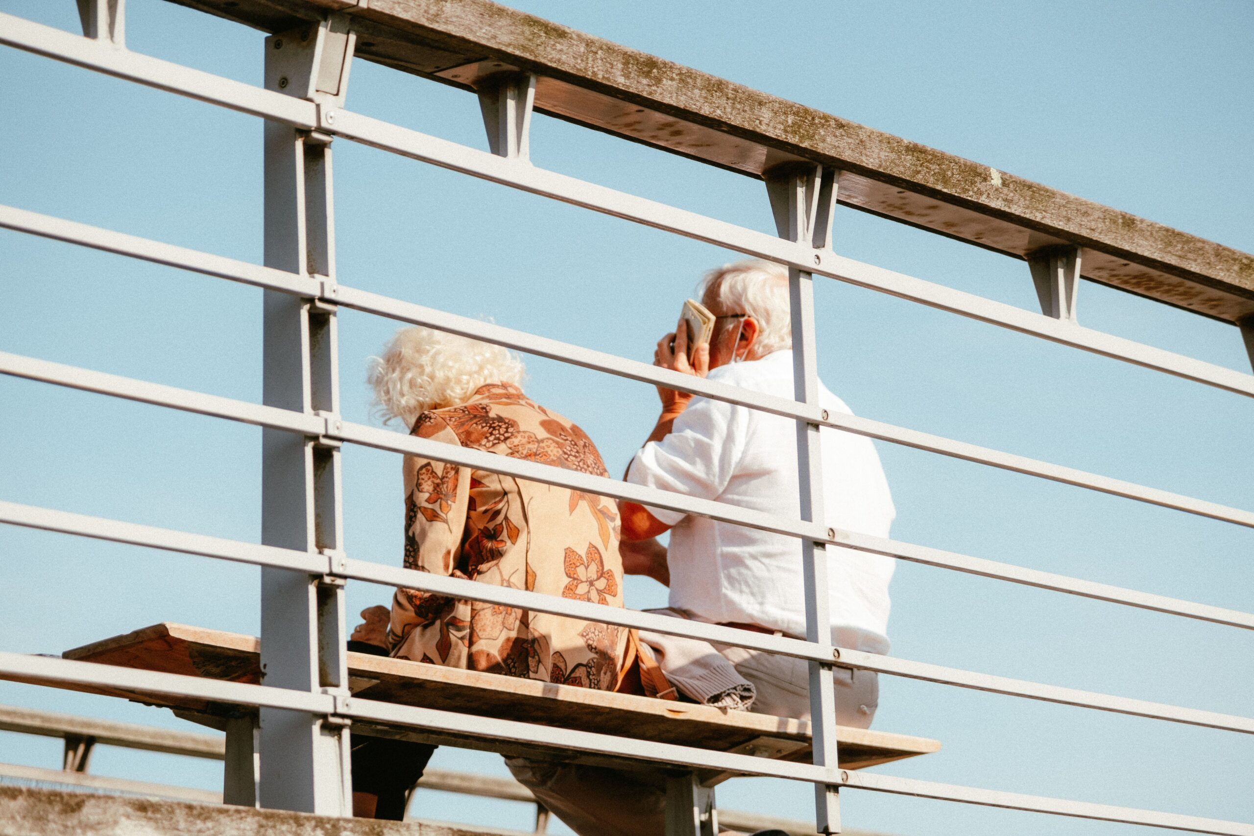 Treppenlift Baden-Württemberg 2026 – Der große Ratgeber zu Kosten, Förderung, Zuschüssen und Anbietern Senior couple sitting on a bench outdoors with blue sky background, enjoying a peaceful moment.