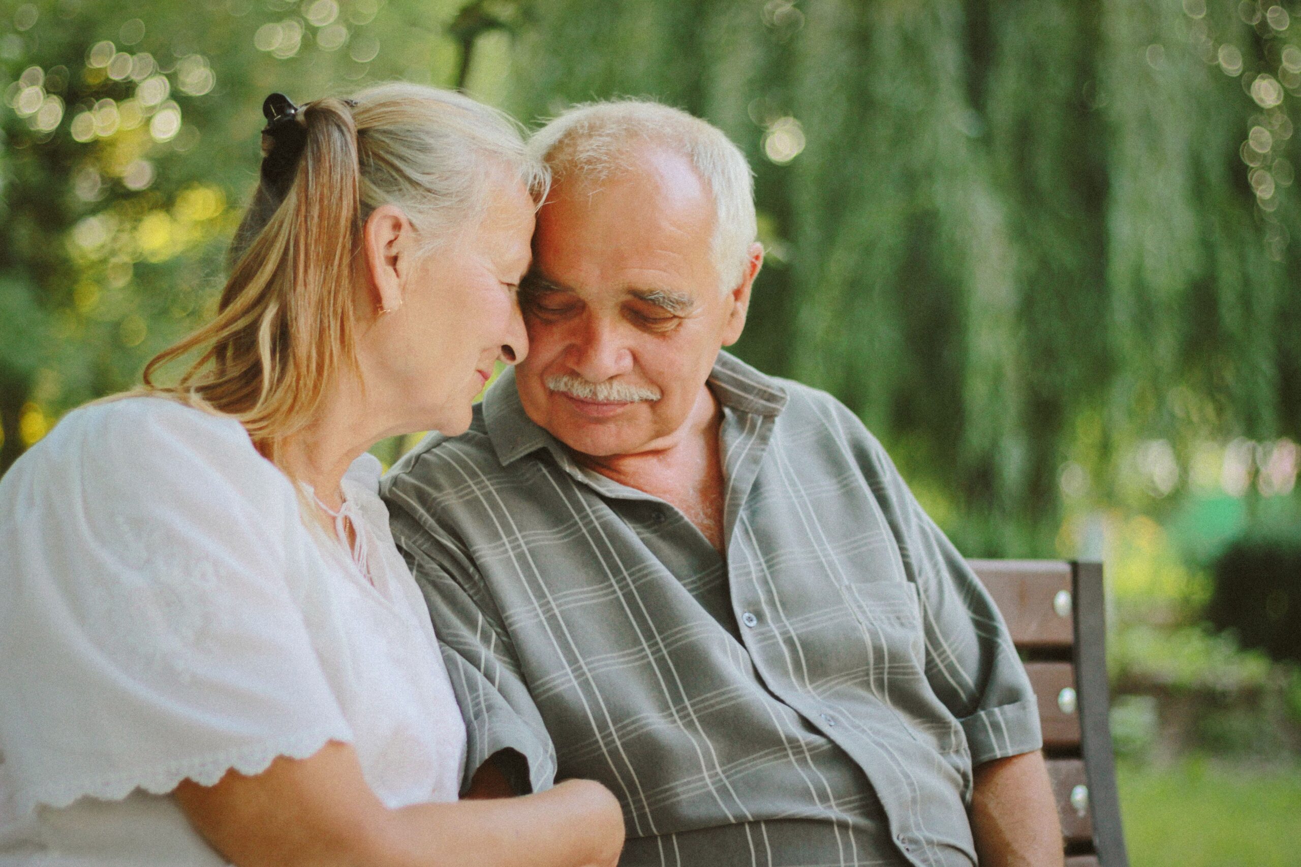 Treppenlift mit Sitz Duisburg – Vorteile im Alltag Elderly couple sitting closely, enjoying a joyful moment together in a serene outdoor setting.