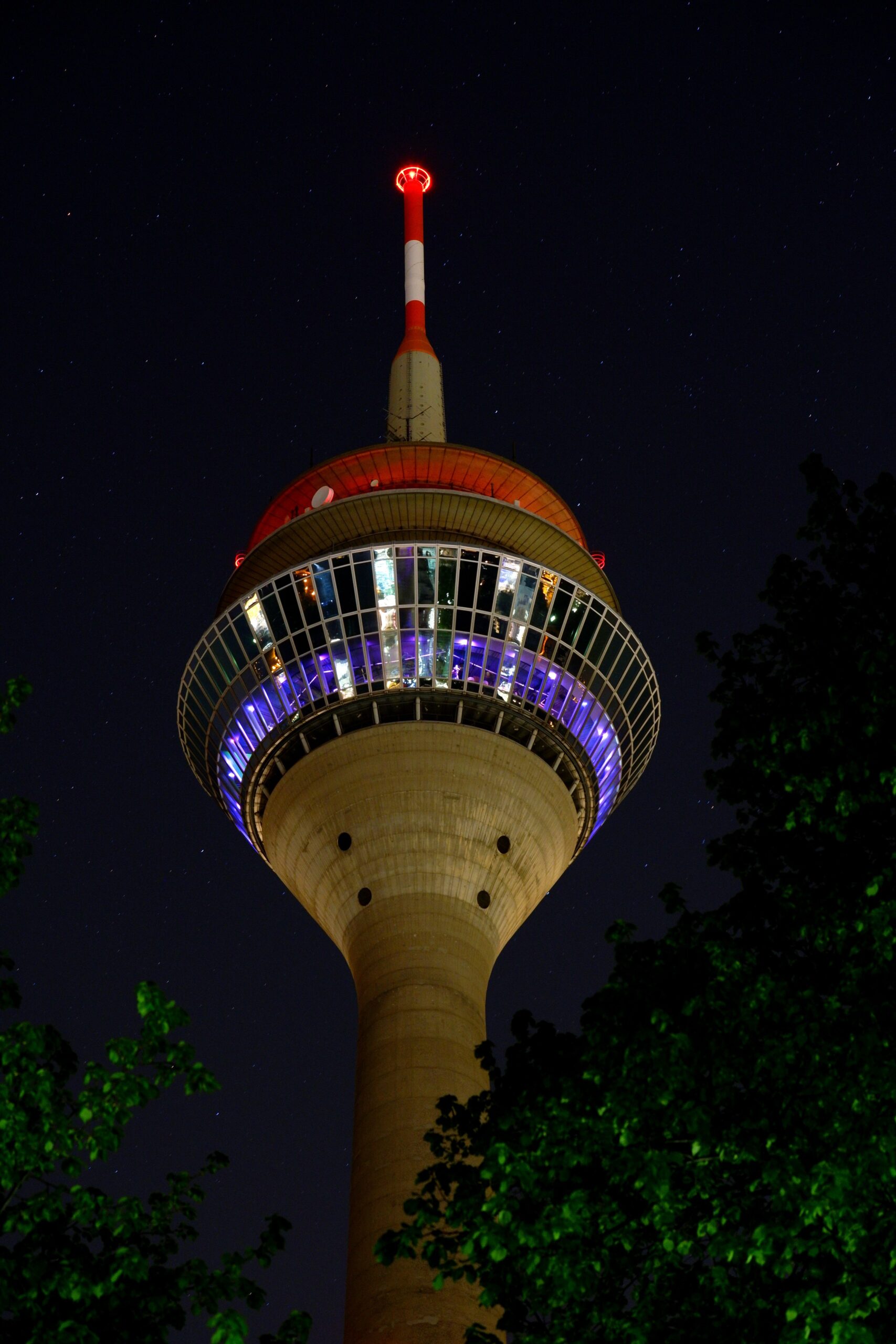 Stunning view of the Rheinturm tower in Düsseldorf illuminated against the night sky.