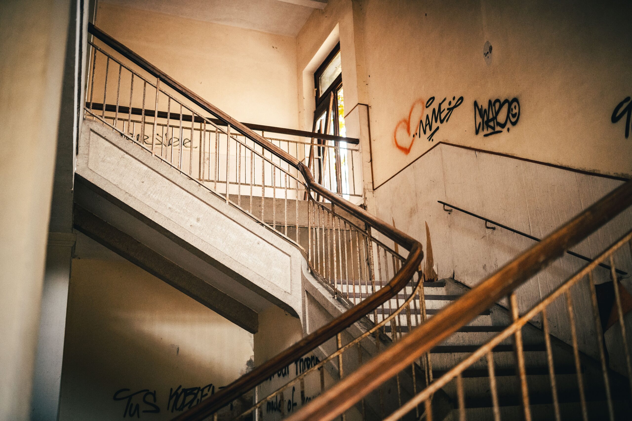 Platzbedarf und Maße von Treppenliften: Technische Voraussetzungen prüfen Explore the abandoned building interior with graffiti-covered stairs and rustic railings, capturing urban decay.
