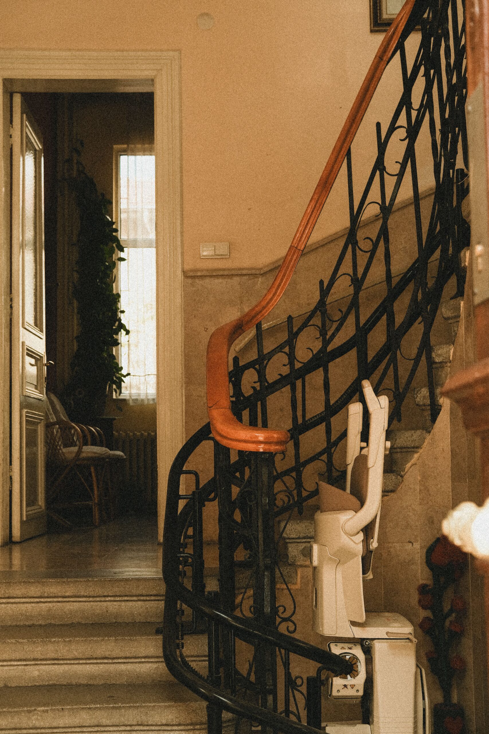 Treppenlift mieten: Vor- und Nachteile im Überblick Beautiful interior staircase with wrought iron railings and stair lift, featuring a warm, inviting atmosphere.