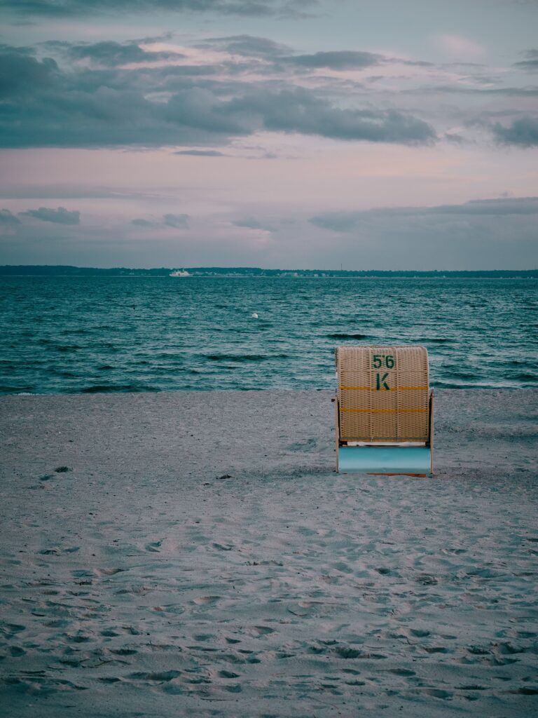 pexels photo 30093395 30093395 Lonely beach chair at sunset on Neustadt in Holstein beach, capturing a serene maritime atmosphere.