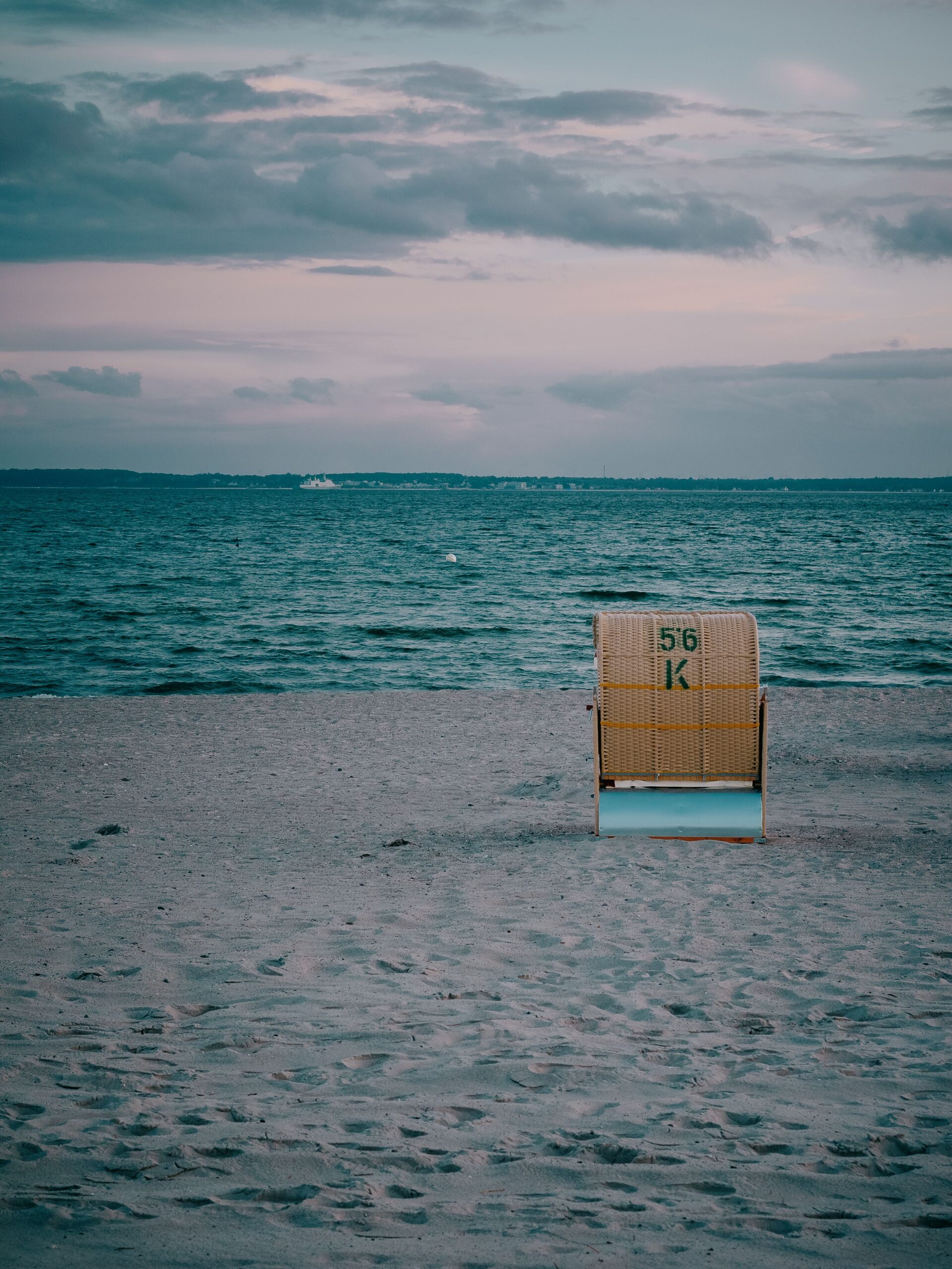 Treppenlift Test Schleswig-Holstein Lonely beach chair at sunset on Neustadt in Holstein beach, capturing a serene maritime atmosphere.