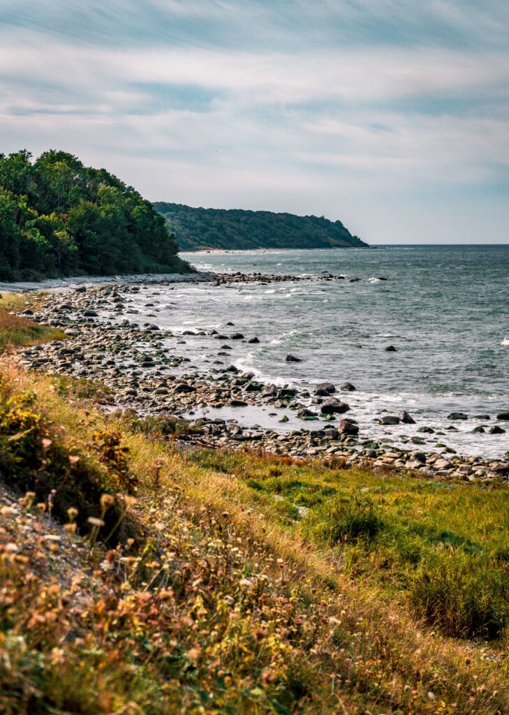 Explore the rocky coastline of Putgarten, Germany with vibrant greenery and the serene sea.
