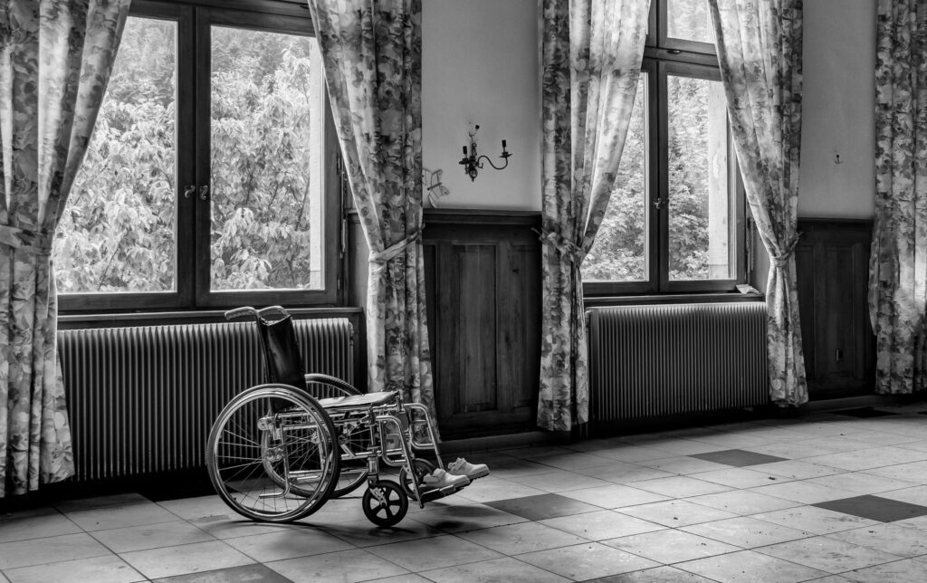 Treppenlift für pflegende Angehörige Gelsenkirchen – Entlastung im Alltag Black and white photo of an empty room with a wheelchair by large windows.